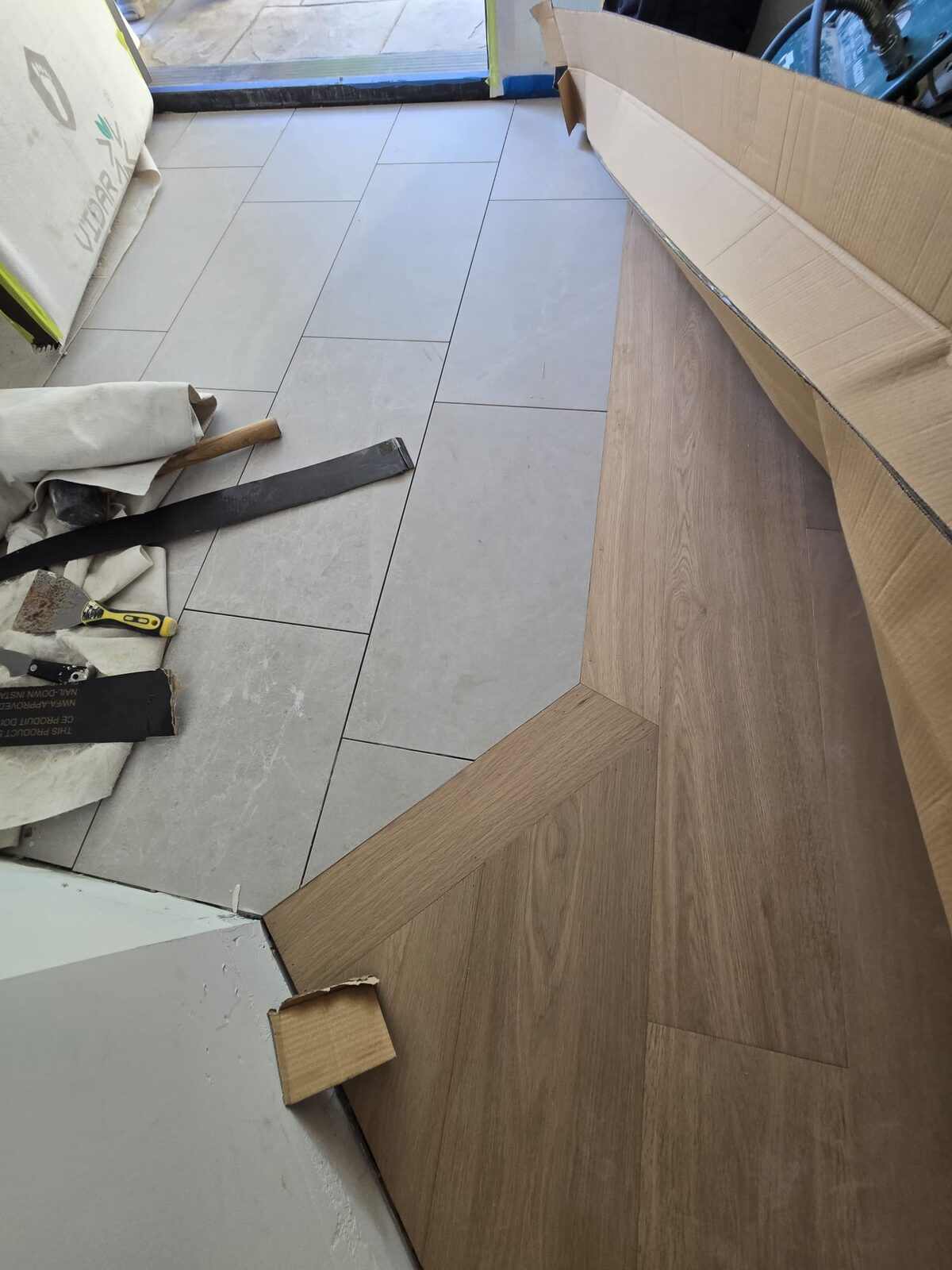 Herringbone hardwood flooring with a clean transition strip installed by ARK Renovation